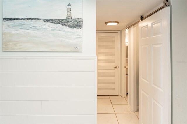 hall featuring a barn door and light tile patterned floors