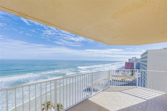 balcony with a water view and a view of the beach