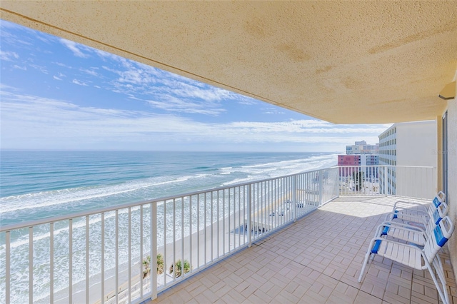 balcony featuring a beach view and a water view