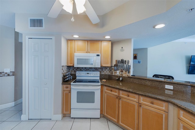 kitchen with white appliances, light tile patterned floors, decorative backsplash, dark stone counters, and ceiling fan