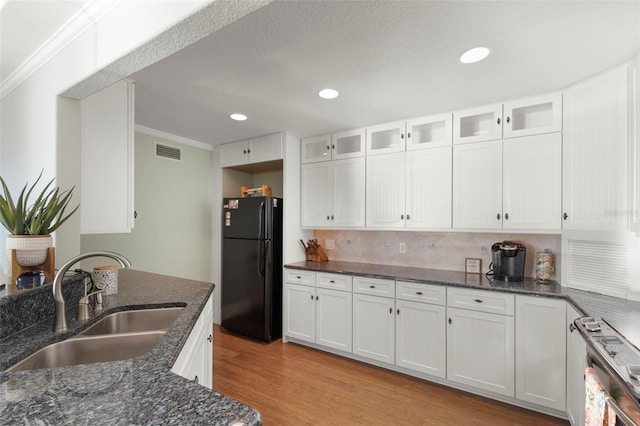 kitchen with light hardwood / wood-style floors, black fridge, white cabinetry, and sink