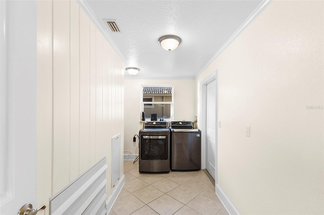 clothes washing area with independent washer and dryer, a textured ceiling, light tile patterned floors, and crown molding