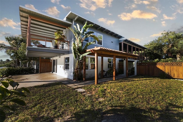 back of property with a pergola, a patio area, and a lawn