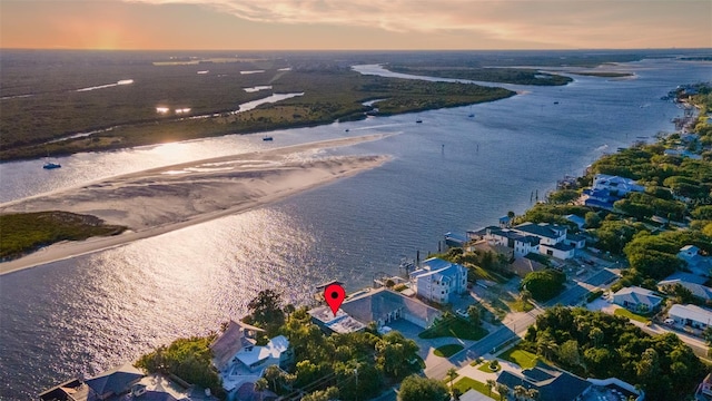 aerial view at dusk with a water view and a beach view