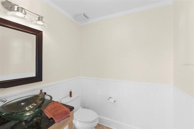 bathroom featuring a wainscoted wall, visible vents, ornamental molding, toilet, and vanity