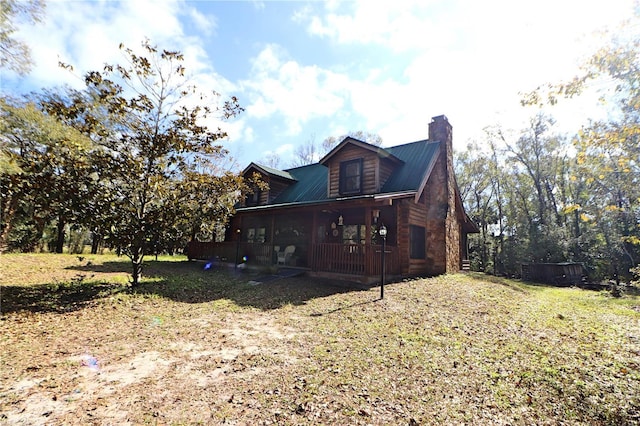 view of side of home featuring a lawn and covered porch