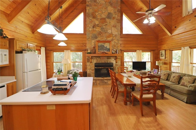 kitchen with pendant lighting, white appliances, high vaulted ceiling, a stone fireplace, and beam ceiling