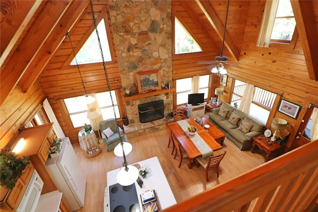 living room with beamed ceiling, light hardwood / wood-style floors, a fireplace, and high vaulted ceiling