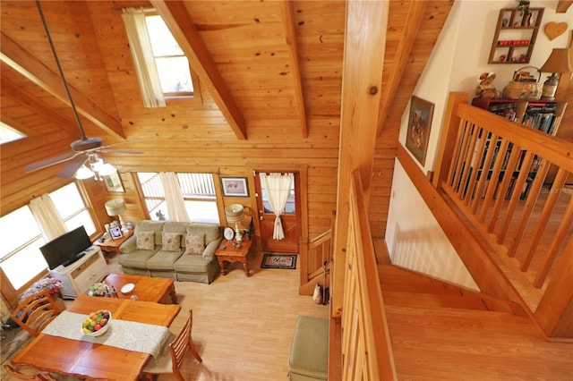 living room with light hardwood / wood-style flooring, high vaulted ceiling, wooden ceiling, beamed ceiling, and wood walls