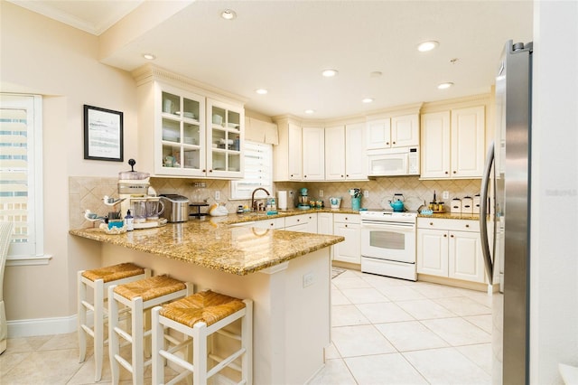 kitchen featuring light stone counters, kitchen peninsula, white appliances, a kitchen bar, and light tile patterned flooring