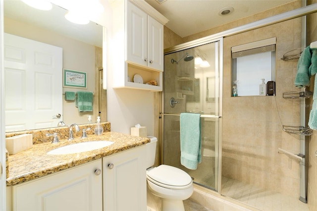 bathroom featuring a shower with door, vanity, and toilet