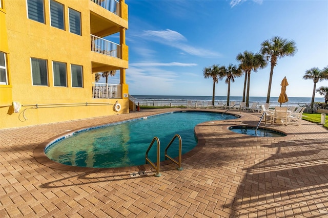 view of swimming pool with a water view and a patio