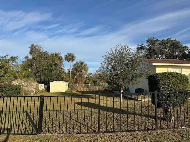 view of gate featuring a yard and a storage unit