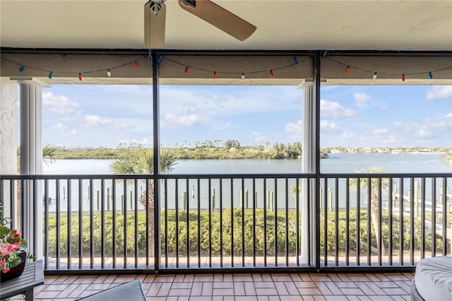 unfurnished sunroom featuring a wealth of natural light, a water view, and ceiling fan