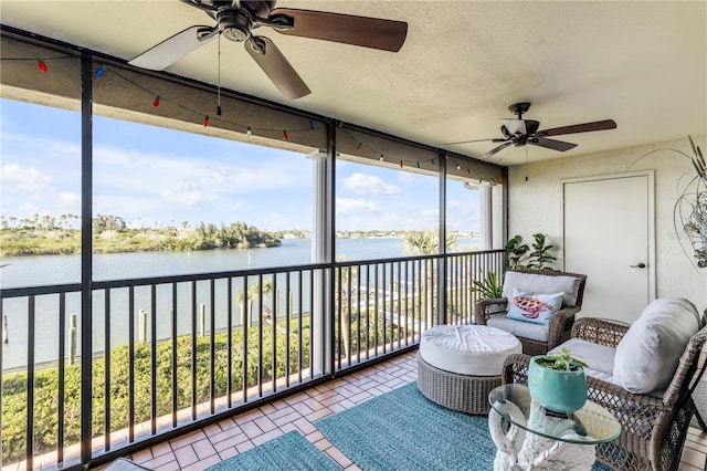 sunroom / solarium featuring a wealth of natural light, a water view, and ceiling fan