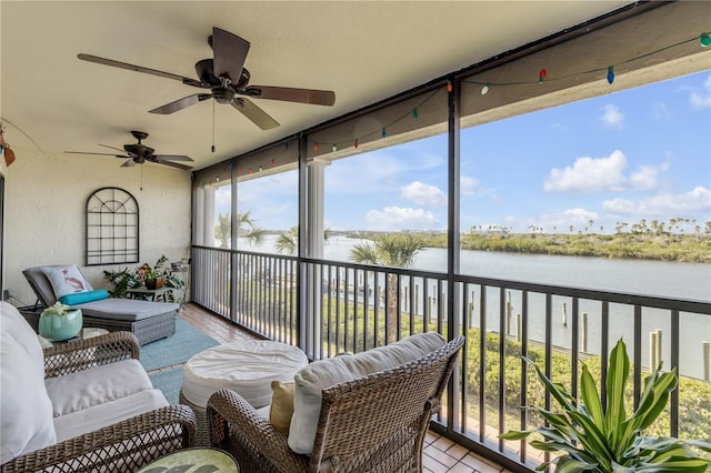 sunroom / solarium featuring a wealth of natural light, ceiling fan, and a water view