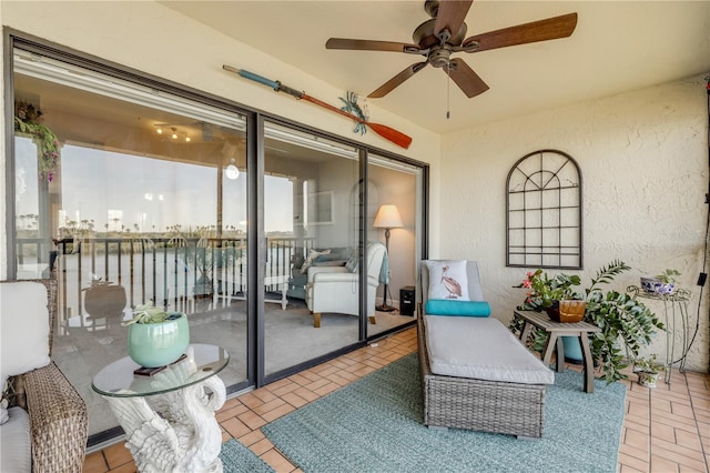 sunroom featuring ceiling fan and a water view