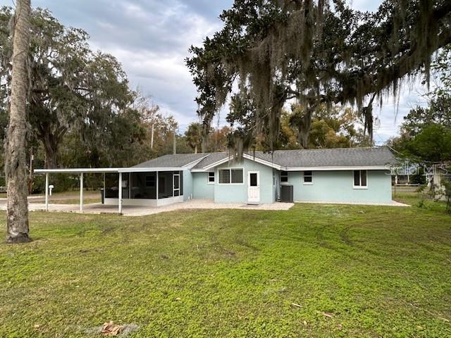 rear view of property with central AC, a sunroom, and a yard