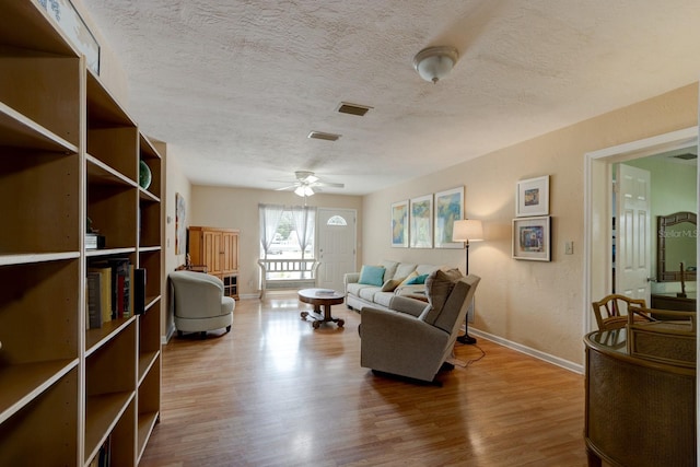 living room featuring hardwood / wood-style flooring, ceiling fan, and a textured ceiling