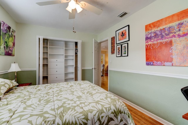 bedroom with ceiling fan, wood-type flooring, and a closet