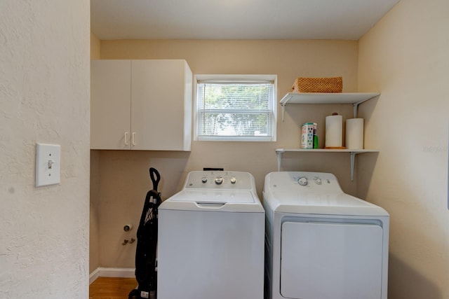 laundry area featuring washing machine and clothes dryer, cabinets, and wood-type flooring