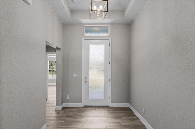 entrance foyer with a raised ceiling and an inviting chandelier