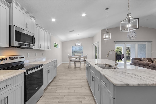 kitchen with appliances with stainless steel finishes, a kitchen island with sink, sink, pendant lighting, and lofted ceiling