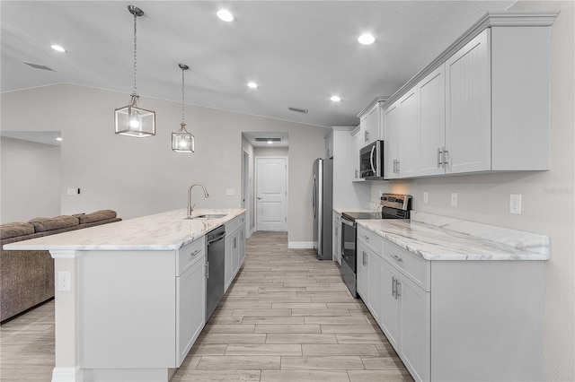 kitchen with appliances with stainless steel finishes, light stone counters, vaulted ceiling, sink, and hanging light fixtures