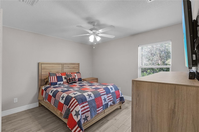 bedroom with ceiling fan, light hardwood / wood-style floors, and a textured ceiling