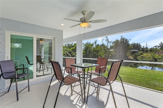 sunroom / solarium with ceiling fan and a water view