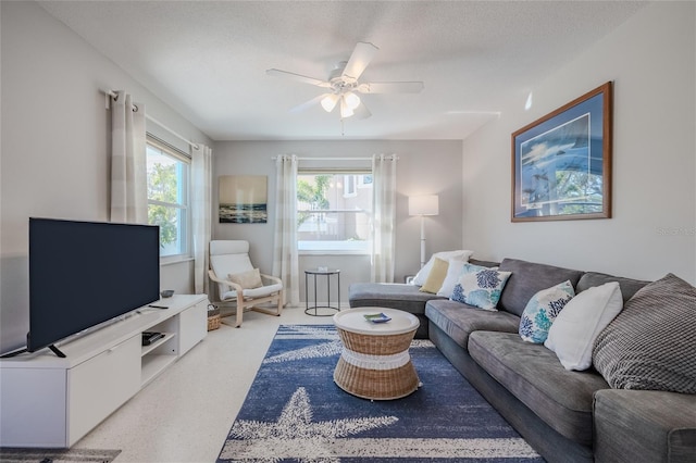 living room featuring ceiling fan and a textured ceiling