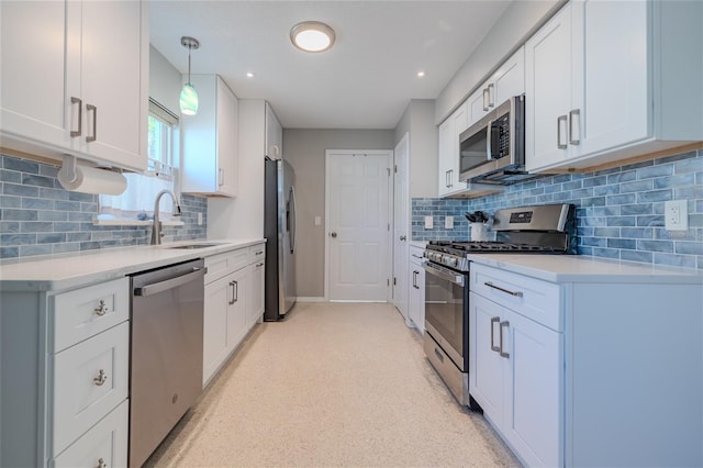 kitchen featuring stainless steel appliances, light countertops, white cabinetry, pendant lighting, and a sink