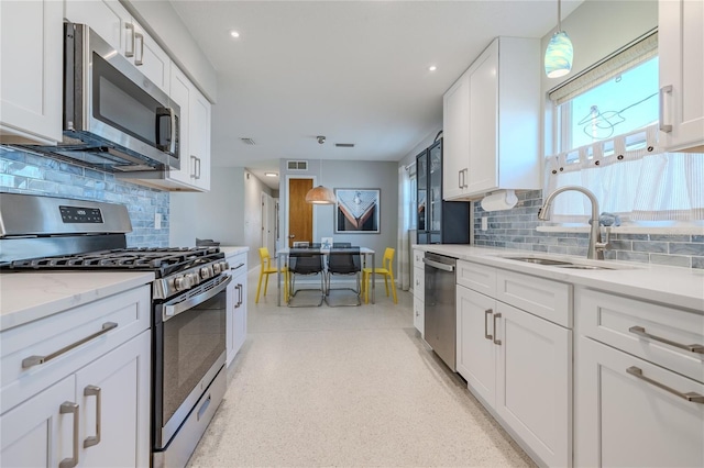 kitchen with white cabinets, decorative light fixtures, and appliances with stainless steel finishes