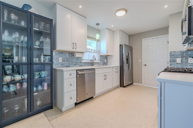 kitchen featuring pendant lighting, sink, tasteful backsplash, white cabinetry, and stainless steel appliances