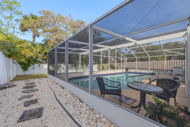 view of swimming pool featuring glass enclosure, a patio, a fenced backyard, and a fenced in pool