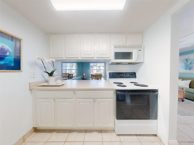 kitchen with light tile patterned flooring, white cabinetry, and range with electric stovetop