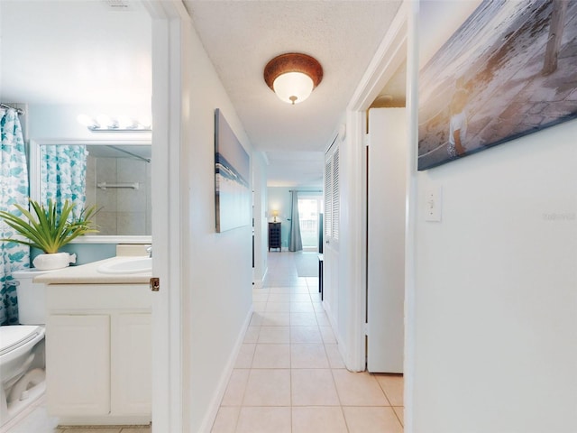 hall featuring sink, a textured ceiling, and light tile patterned floors