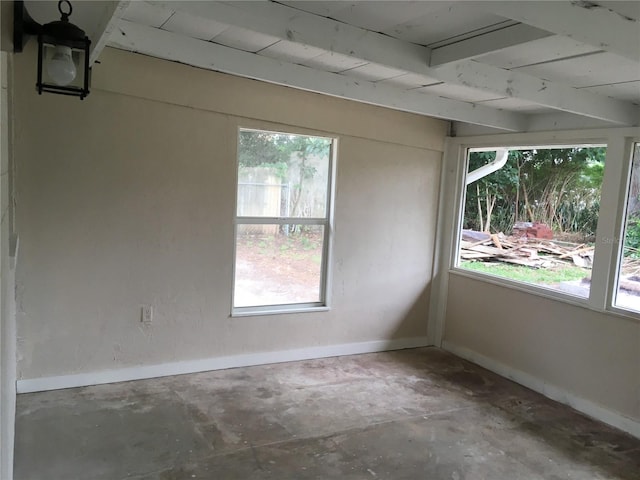 empty room with a healthy amount of sunlight, wood ceiling, beam ceiling, and concrete floors