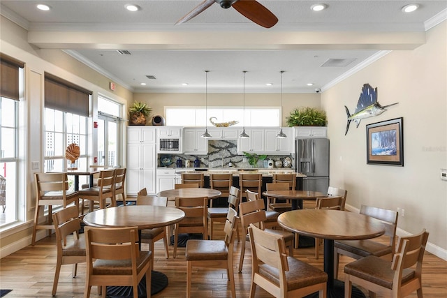 dining space with light wood-type flooring, plenty of natural light, and crown molding