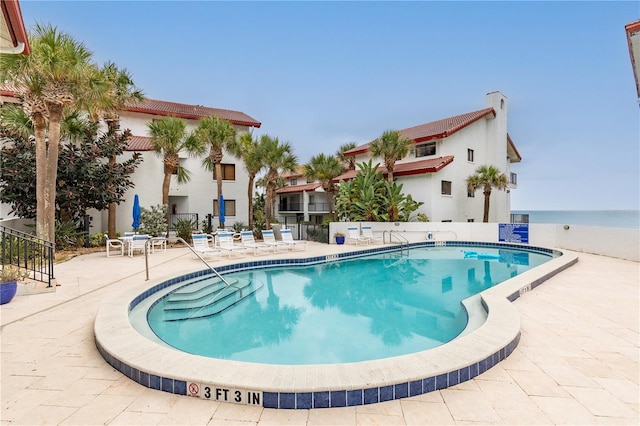 view of pool with a patio and a water view