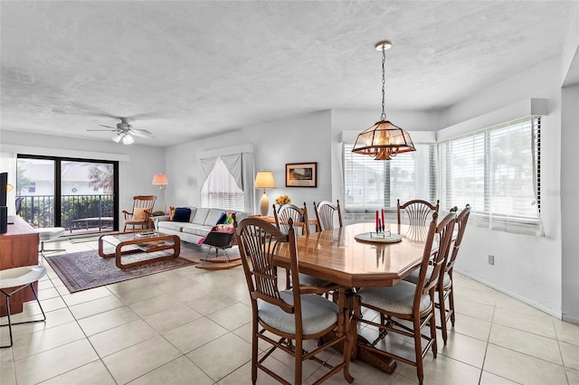 tiled dining space with a healthy amount of sunlight and ceiling fan with notable chandelier