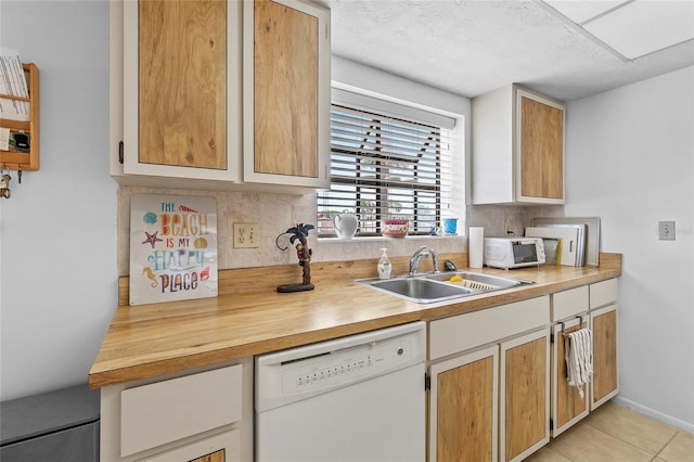 kitchen with sink, a textured ceiling, light tile patterned floors, and dishwasher