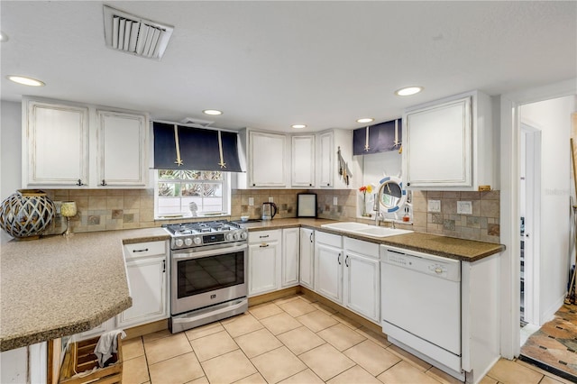 kitchen with dishwasher, sink, light tile patterned floors, high end stove, and white cabinets