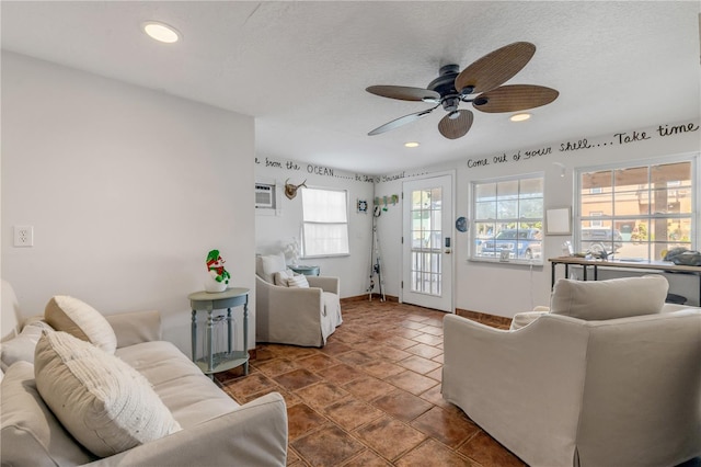 living room featuring a wall mounted AC, ceiling fan, and a textured ceiling