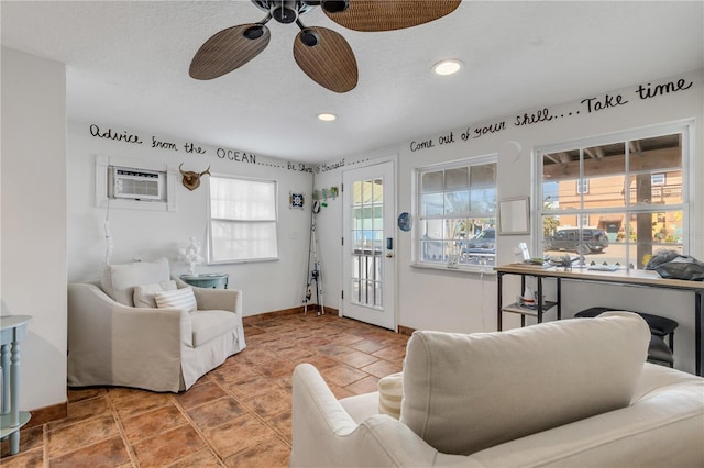 living room featuring an AC wall unit, ceiling fan, tile patterned flooring, and a textured ceiling