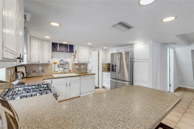 kitchen with white dishwasher, sink, white cabinetry, and stainless steel refrigerator with ice dispenser