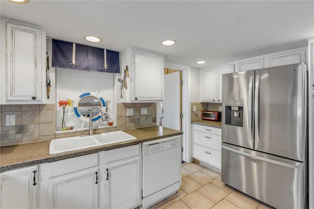 kitchen featuring stainless steel refrigerator with ice dispenser, white dishwasher, sink, white cabinets, and light tile patterned flooring