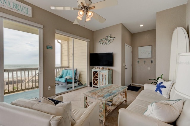 living room featuring a water view, ceiling fan, and light tile patterned flooring