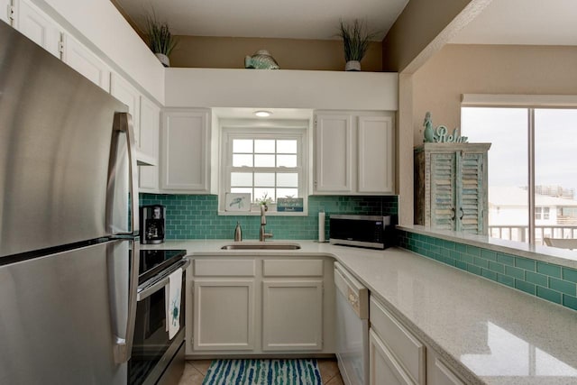 kitchen with light tile patterned floors, sink, white cabinetry, and appliances with stainless steel finishes