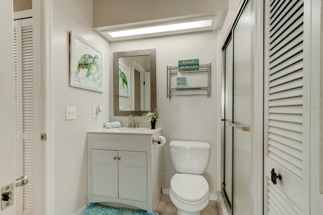 bathroom featuring a shower with door, tile patterned floors, toilet, and vanity